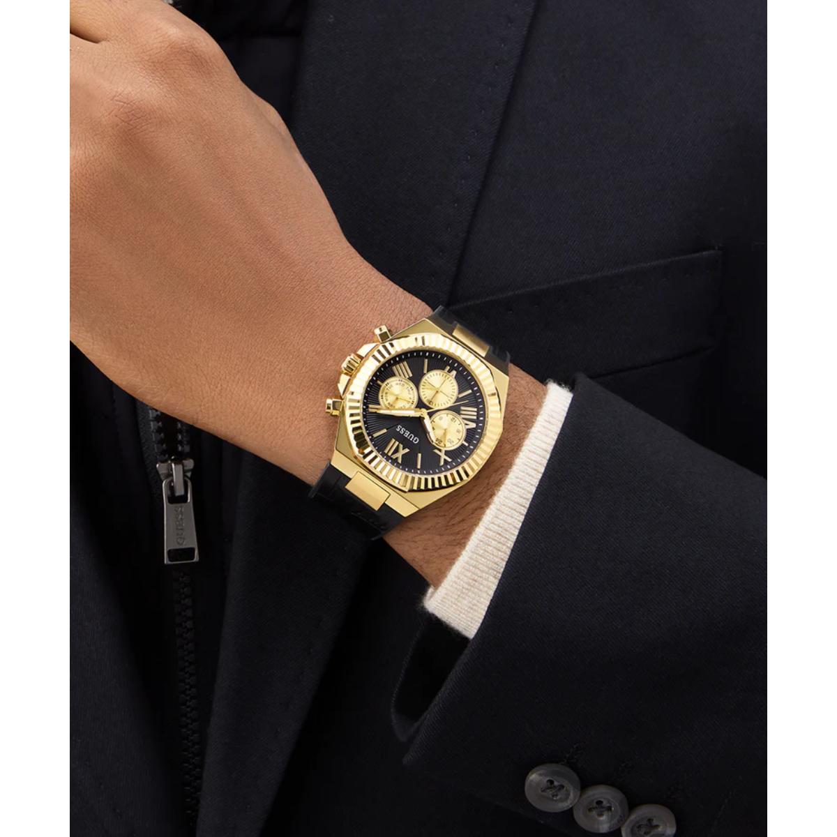 Gold wristwatch on a person wearing a dark suit with a white shirt cuff.