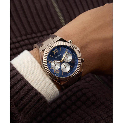 Wrist wearing a rose gold watch with a blue face on a dark background