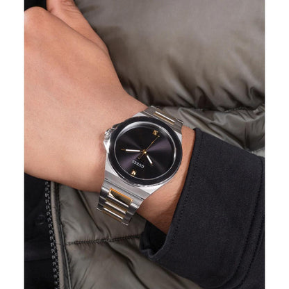 Silver watch on a wrist with a gray jacket background