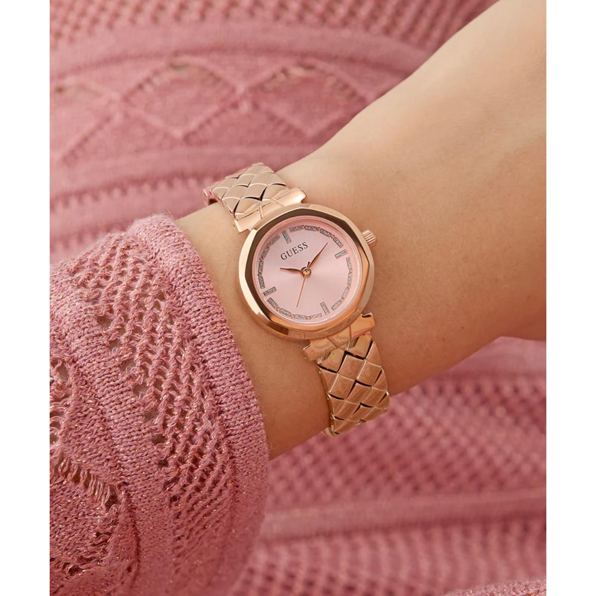 Rose gold watch on a wrist with a pink textured background