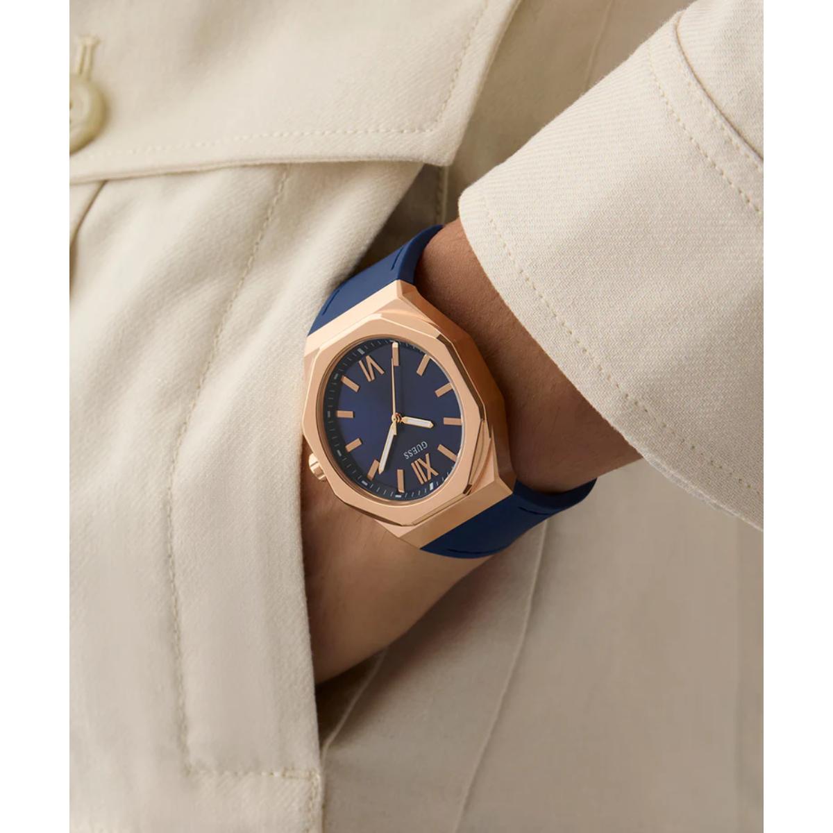 Watch with blue strap and rose gold case on wrist wearing a beige coat