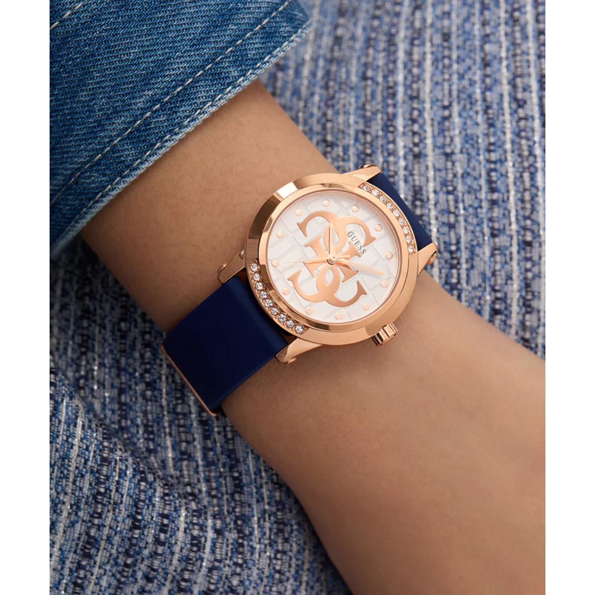 Wrist wearing a watch with a blue strap and rose gold case on a denim background
