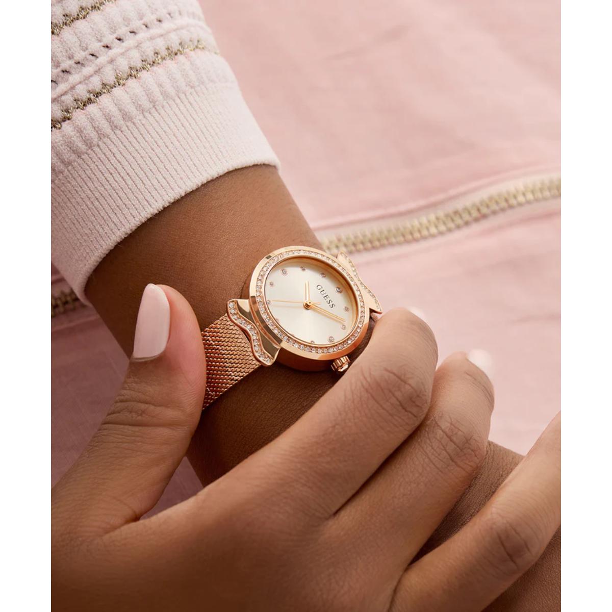 Rose gold watch on a wrist with a pink background