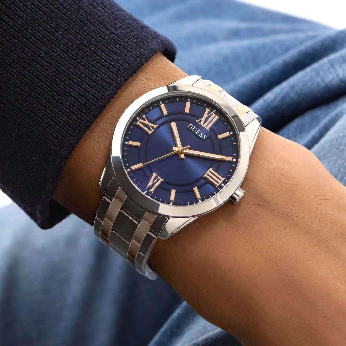 Silver watch with a blue face on a wrist, brand 'Guess' visible
