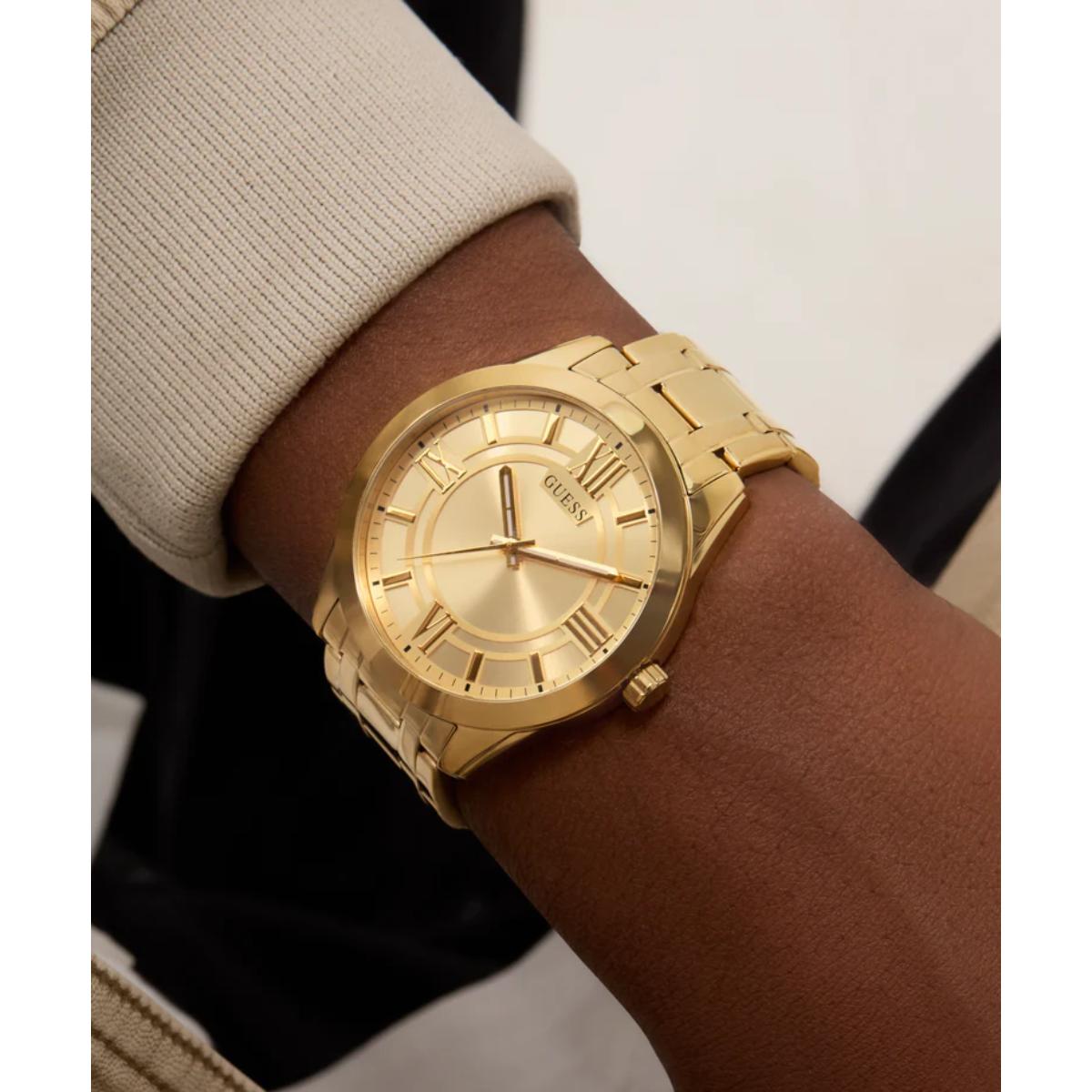 Gold watch on a wrist with a neutral background
