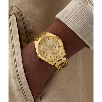 Gold wristwatch on a wrist with a brown strap, wearing a beige jacket.