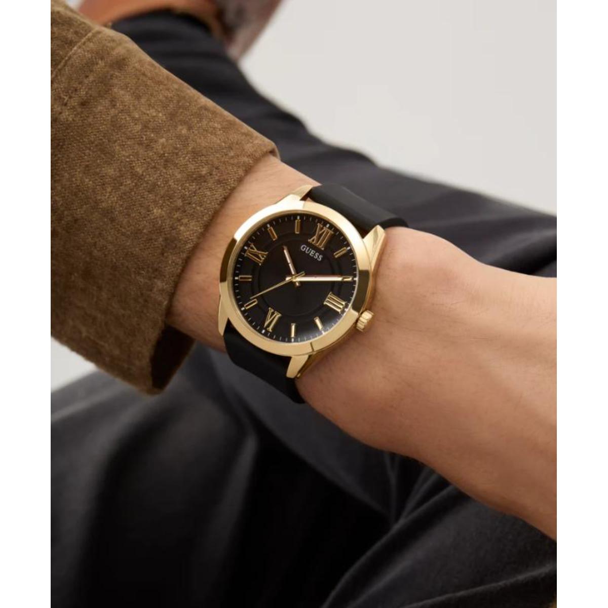 Gold watch with black strap on a wrist against a neutral background
