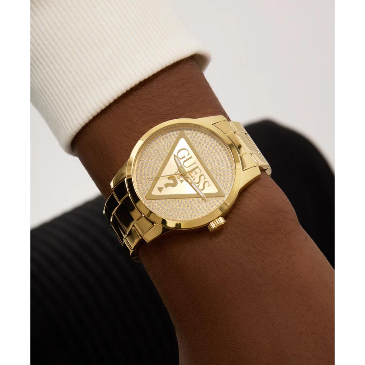 Gold watch with triangle logo on wrist against a neutral background