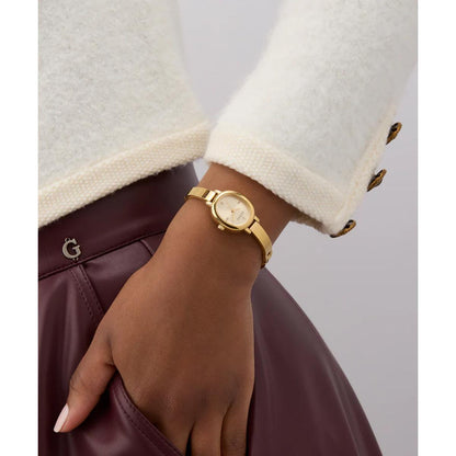 Gold watch on a wrist with a neutral background