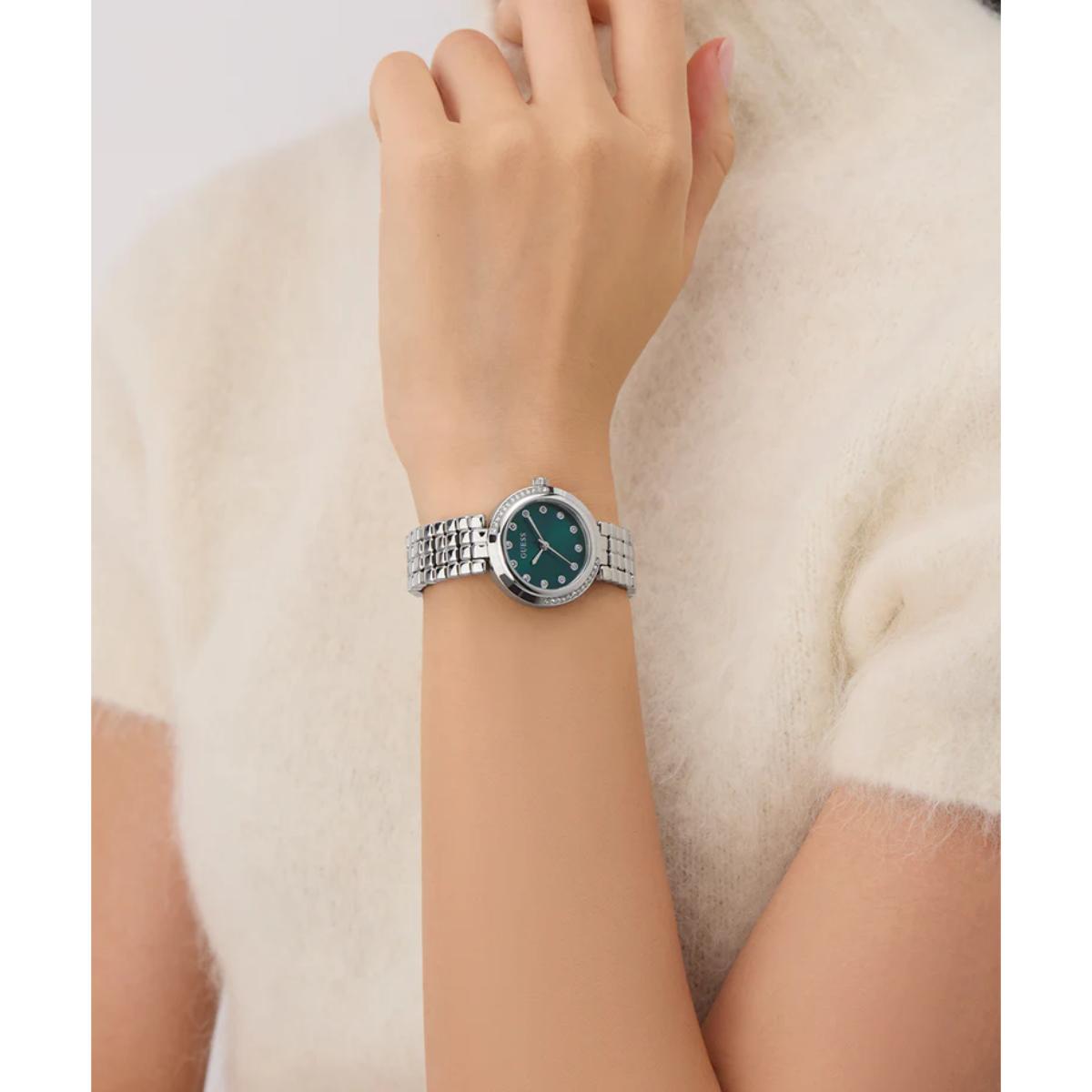Silver watch with a green face on a wrist against a white background