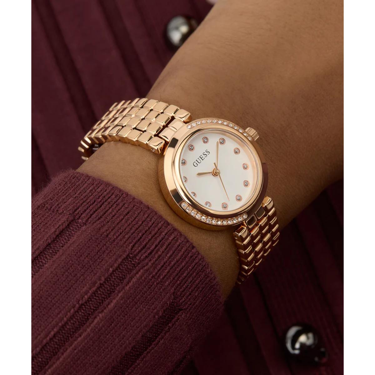 Gold watch on a wrist with a maroon background