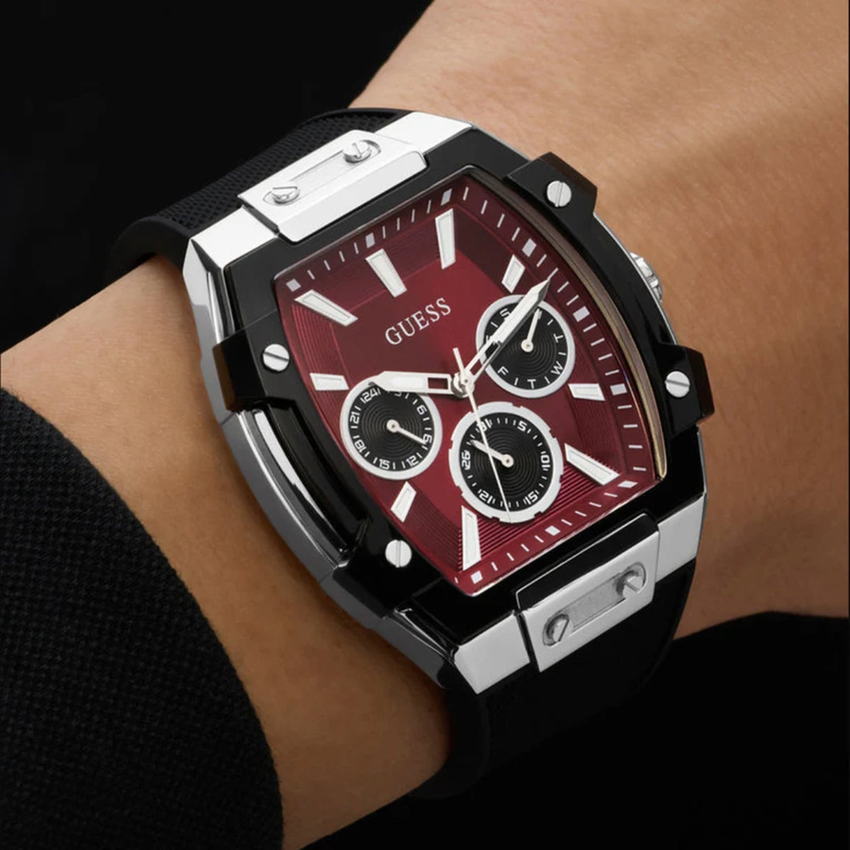 Black and red Guess watch on a wrist with a dark background