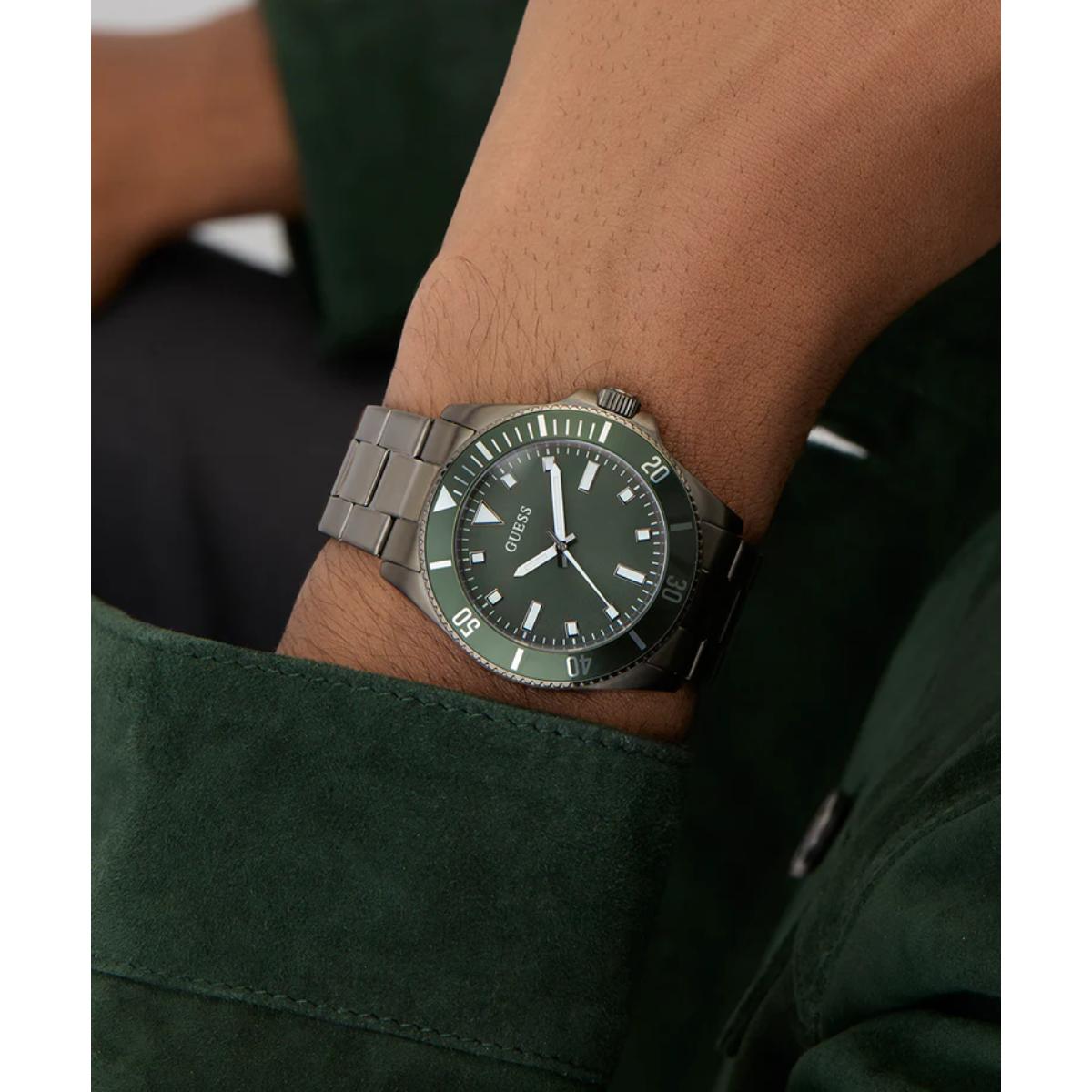 Green watch with silver band on a person's wrist, wearing a dark green shirt.