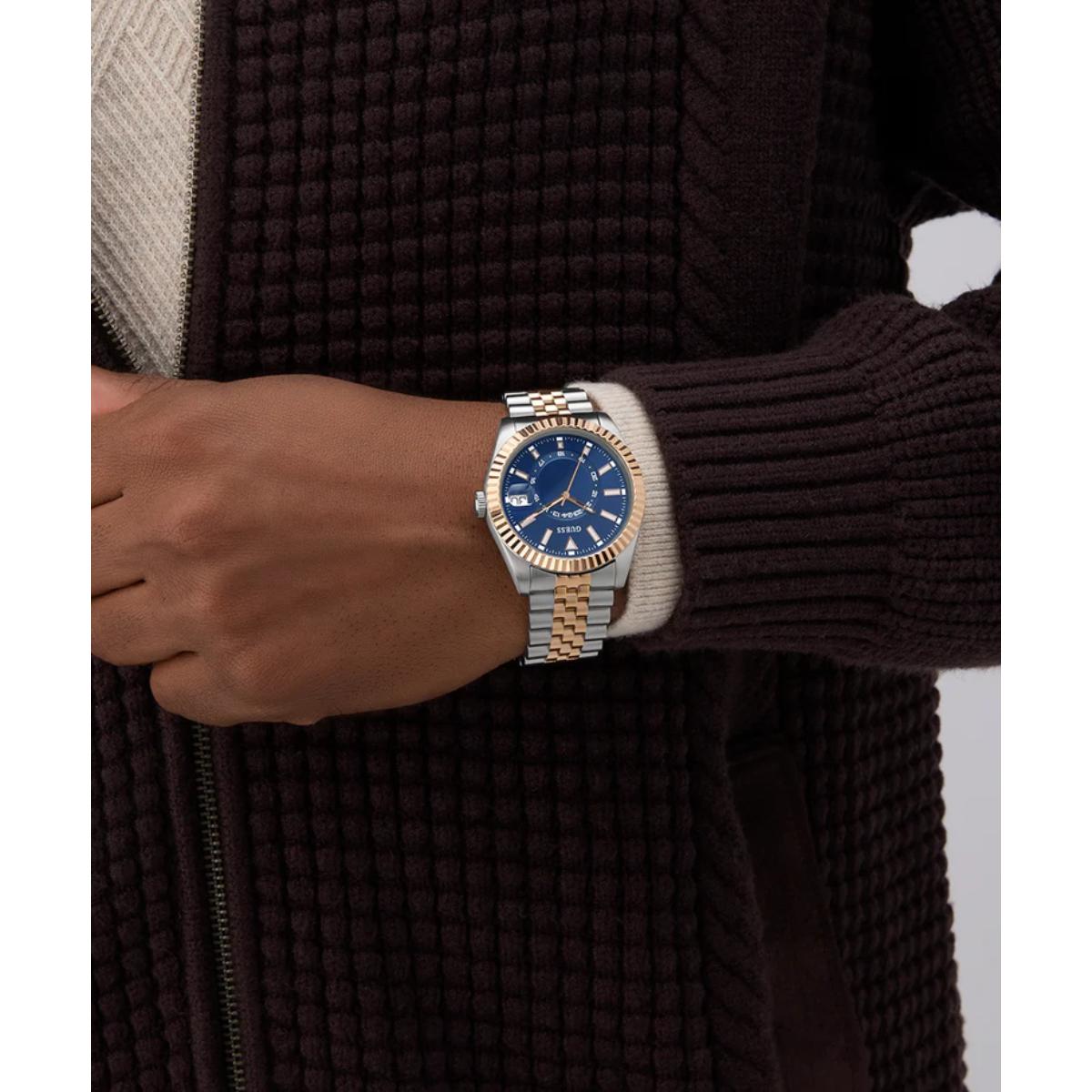 Person wearing a two-tone watch with a blue face on a dark sweater background