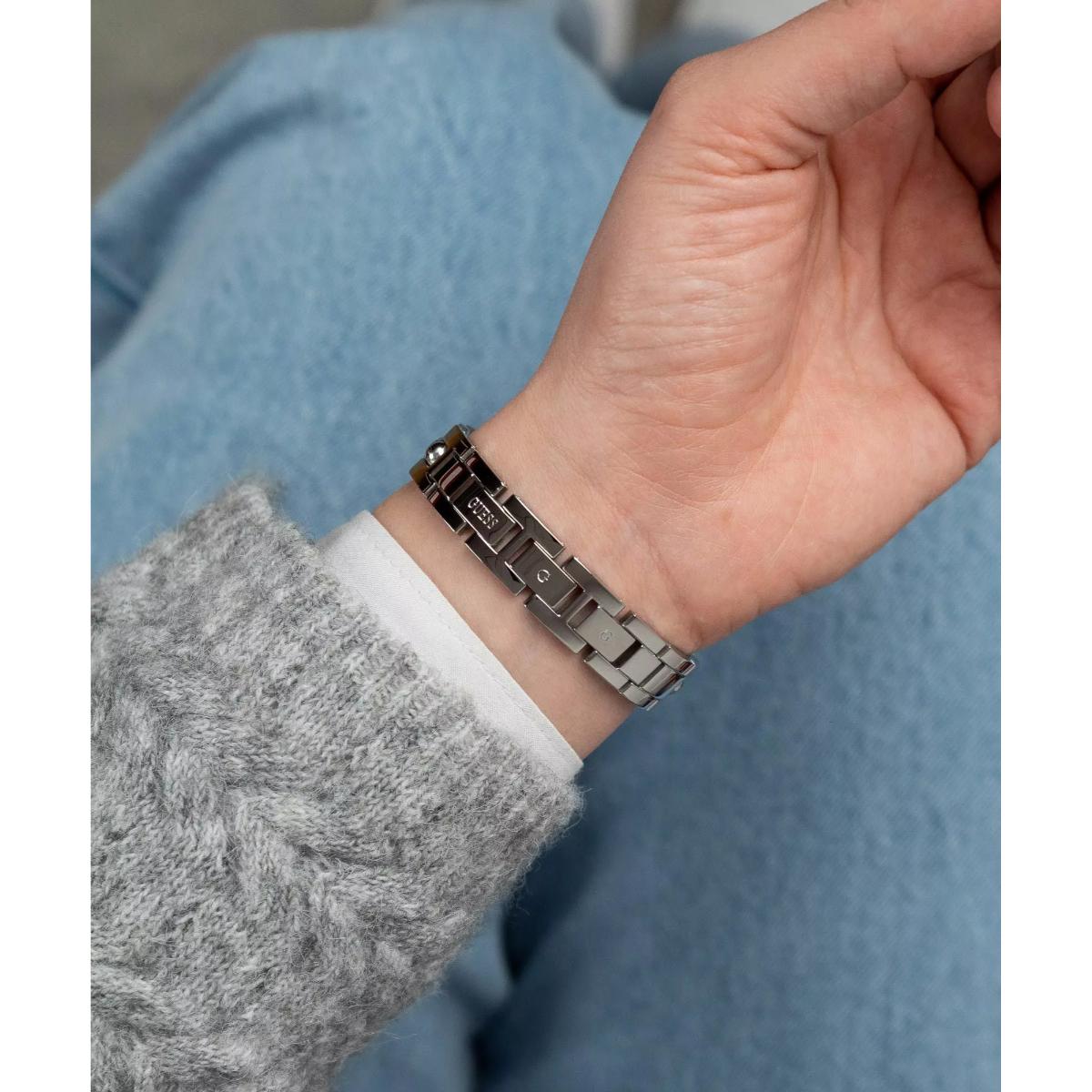 Close-up of a hand wearing a metallic bracelet with a blurred background