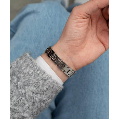 Close-up of a hand wearing a metallic bracelet with a blurred background