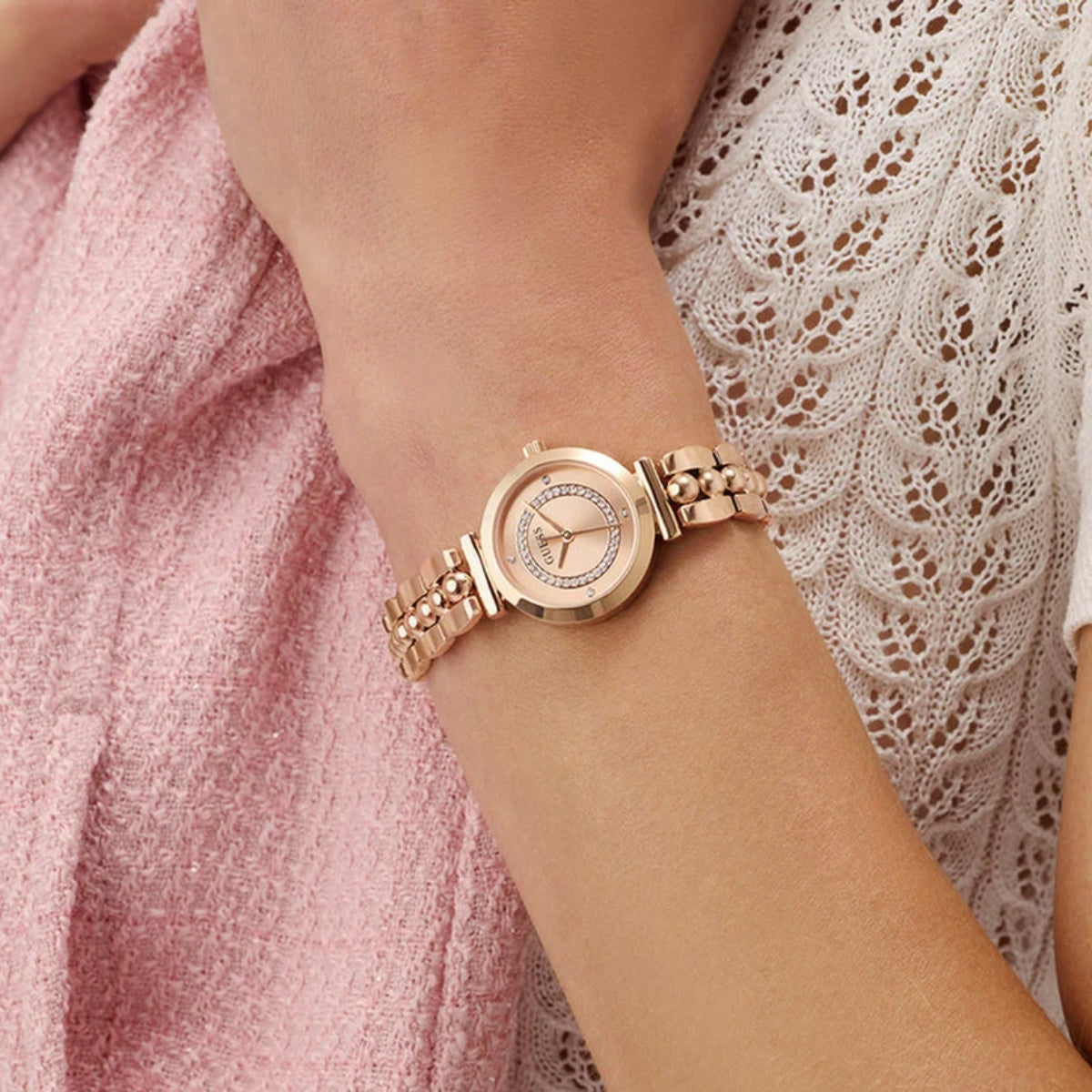 Rose gold watch on a wrist with a soft focus background