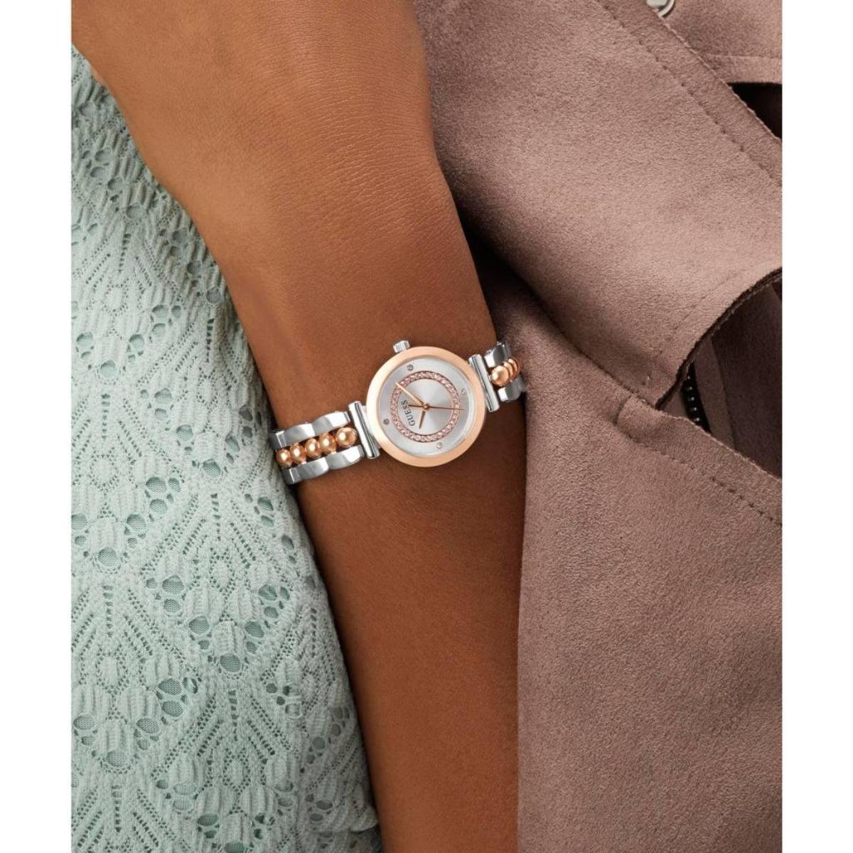 Silver and rose gold watch on a wrist with a brown coat and green lace background