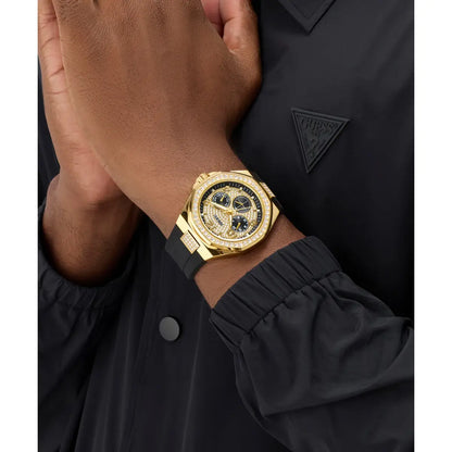 A close-up of a person wearing a Guess wristwatch with a gold-tone case, black dial, and black strap, paired with a black Guess jacket.