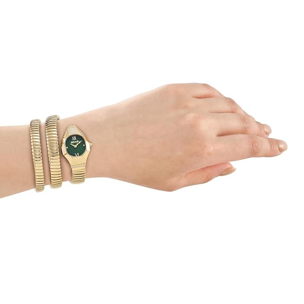Hand wearing a gold watch with a green face on a white background