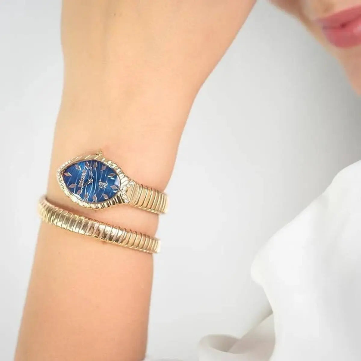 Gold bracelet with a blue stone on a wrist against a white background