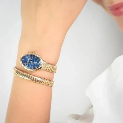 Gold bracelet with a blue stone on a wrist against a white background