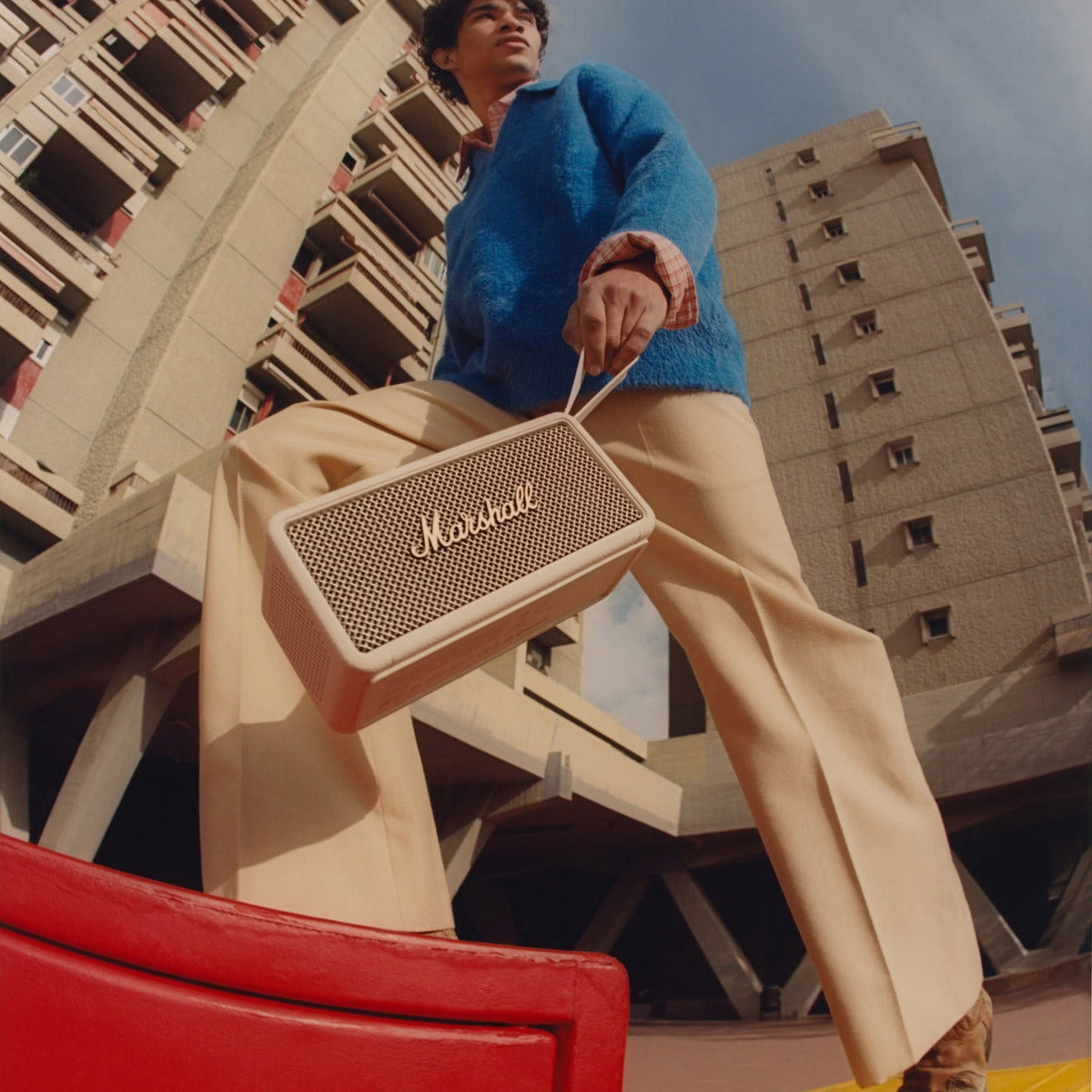 Person holding a Marshall speaker against an urban background