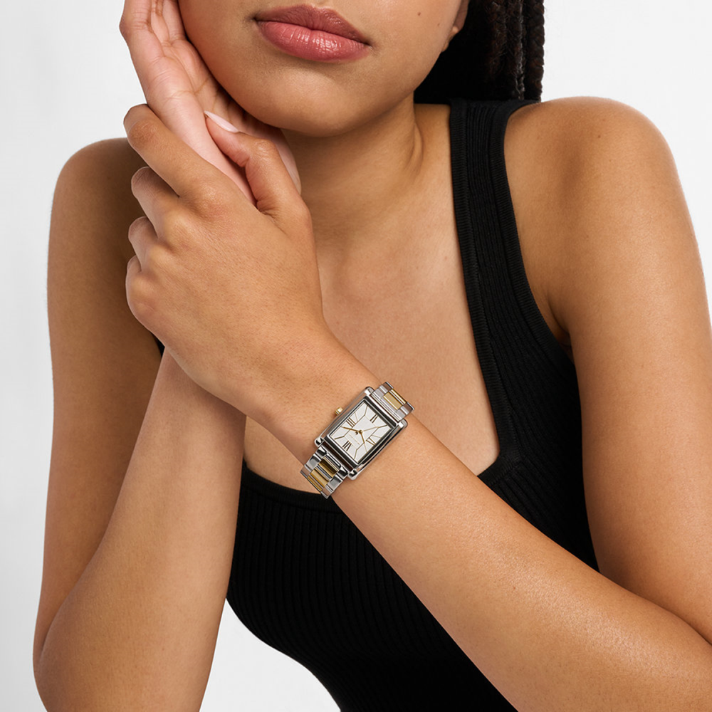 Woman wearing a silver watch on a plain background