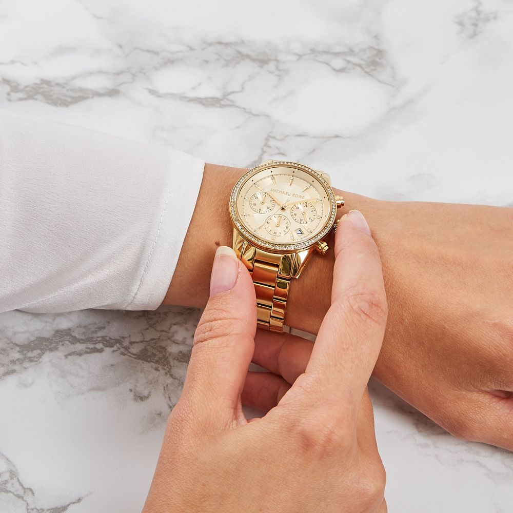Gold watch on a wrist with a marble background