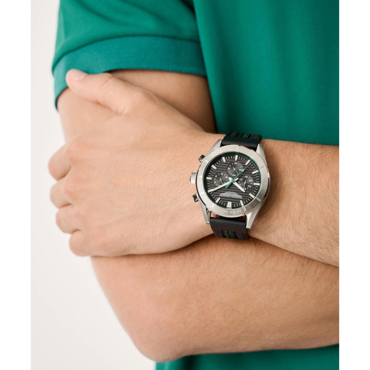 Person wearing a silver watch with a green shirt on a white background