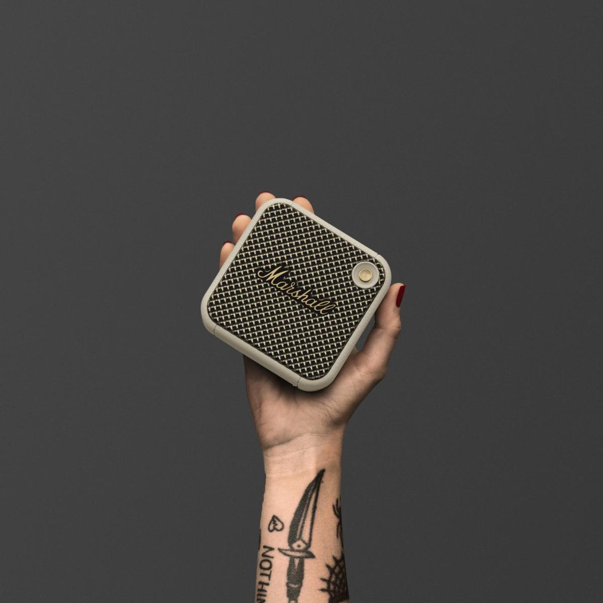Hand holding a small square device with a textured surface against a dark background