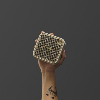 Hand holding a Marshall speaker against a dark background