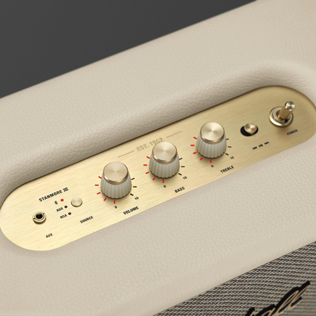 Control panel of a speaker with knobs and labels on a beige surface