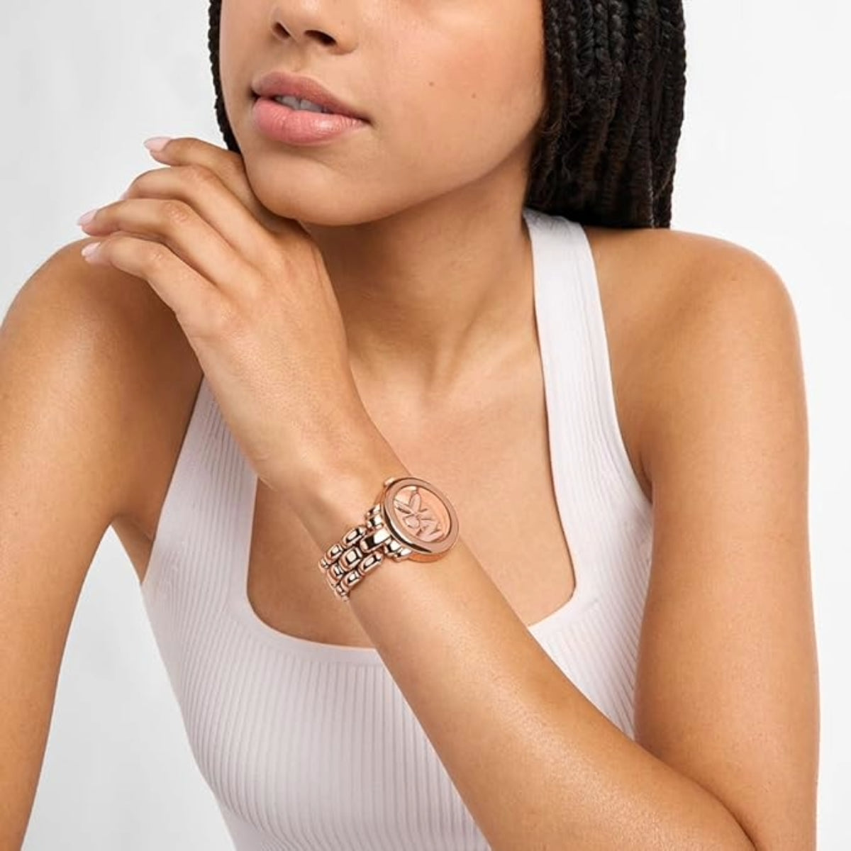 Woman wearing a rose gold watch and bracelet on a plain background