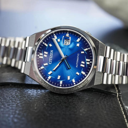 Citizen watch with blue face and silver metal strap on a dark textured surface