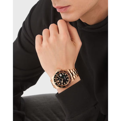 Person wearing a rose gold watch with a black face on a plain background