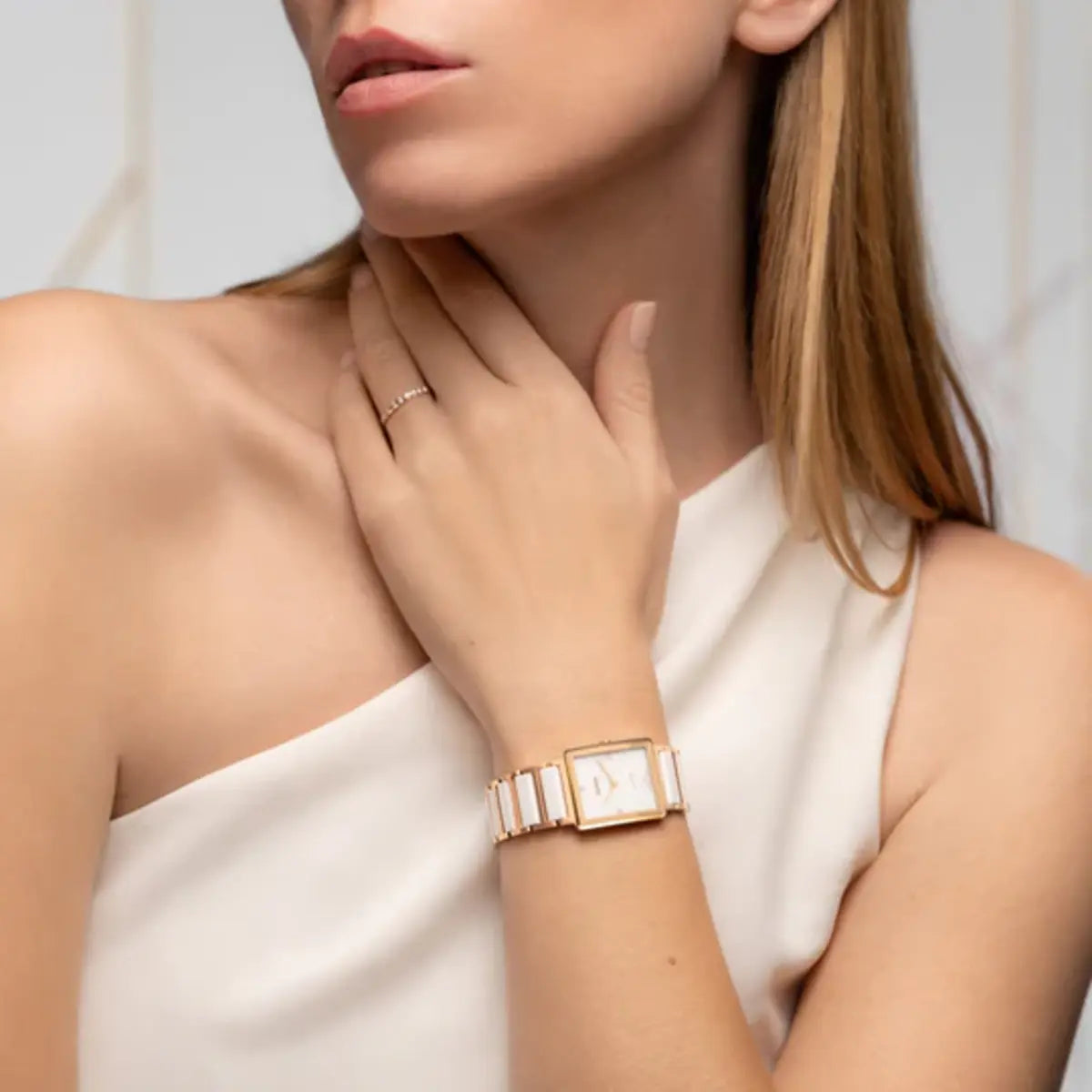 Woman wearing a gold watch on a plain background