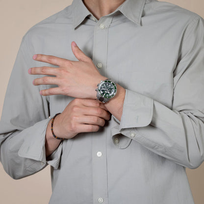 Person wearing a gray shirt and a watch with a beige background