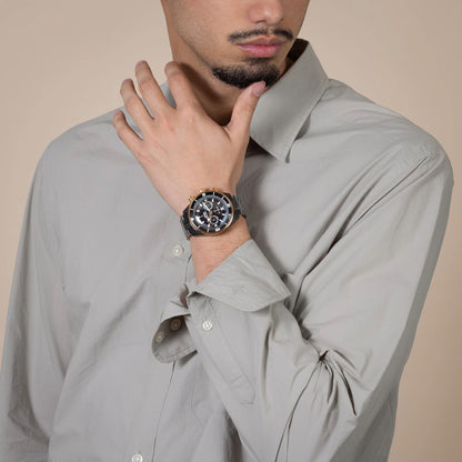 Man wearing a gray shirt with a watch on his wrist against a beige background