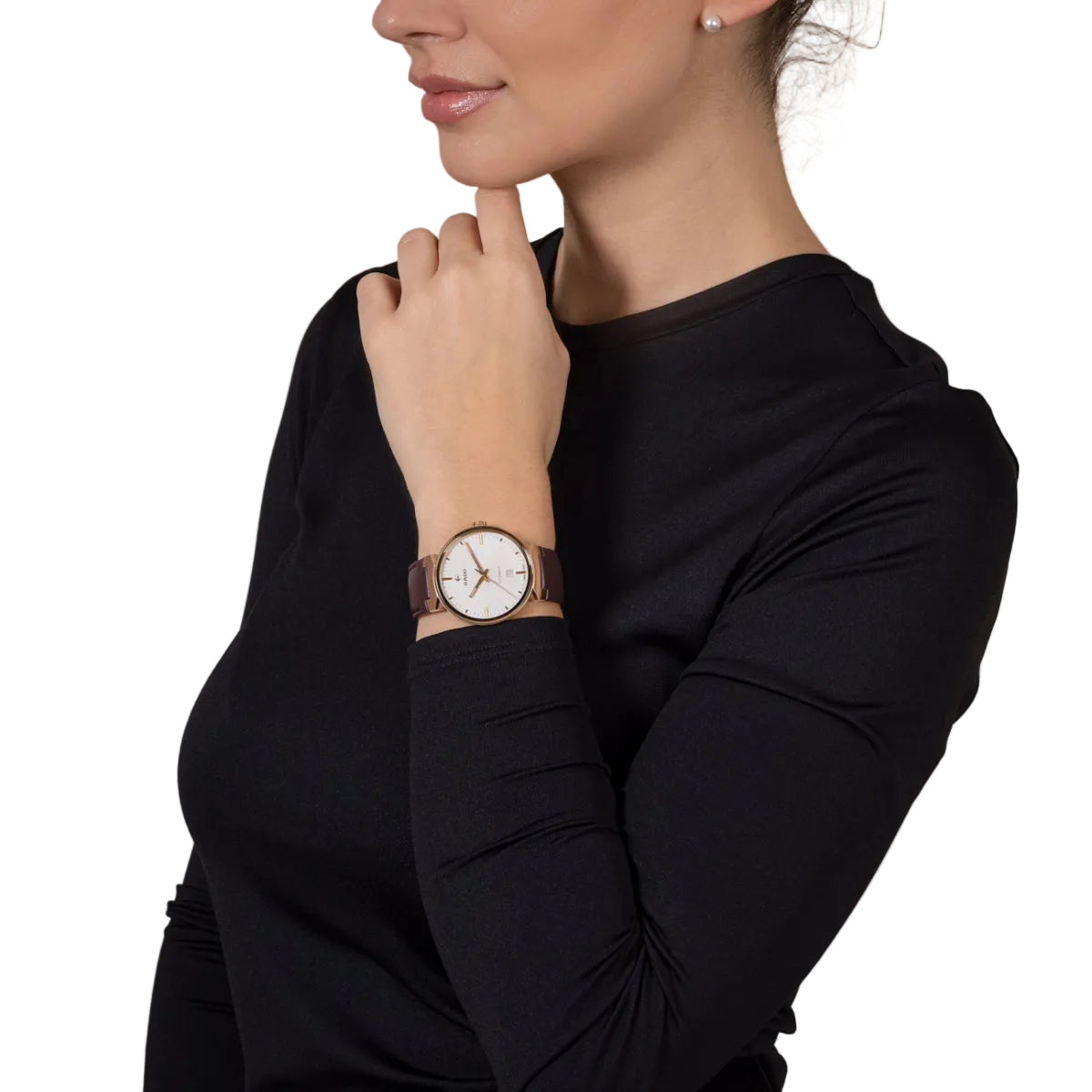 Woman wearing a black long-sleeve top with a watch on her wrist against a beige background