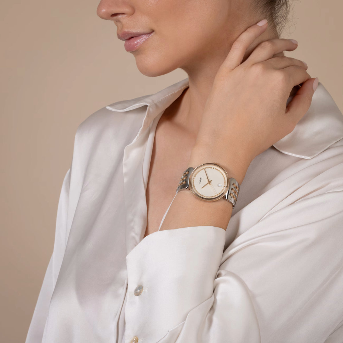 Woman wearing a gold watch with a beige background