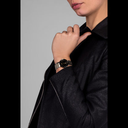 Person wearing a black jacket and a watch on a gray background