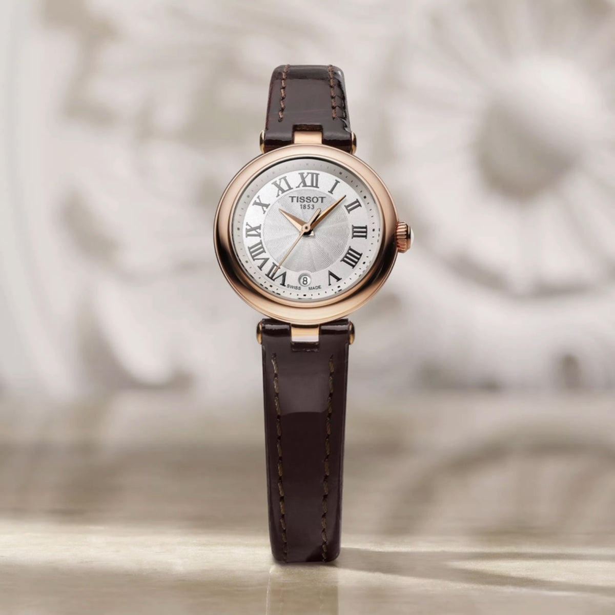 Tissot watch with brown leather strap on a neutral background