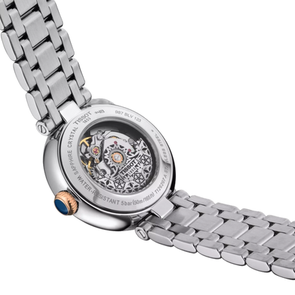 Close-up of a silver watch with a detailed mechanical movement on a white background
