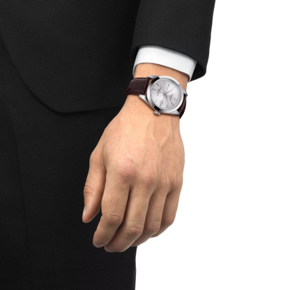 Hand wearing a wristwatch with a brown leather strap on a white background