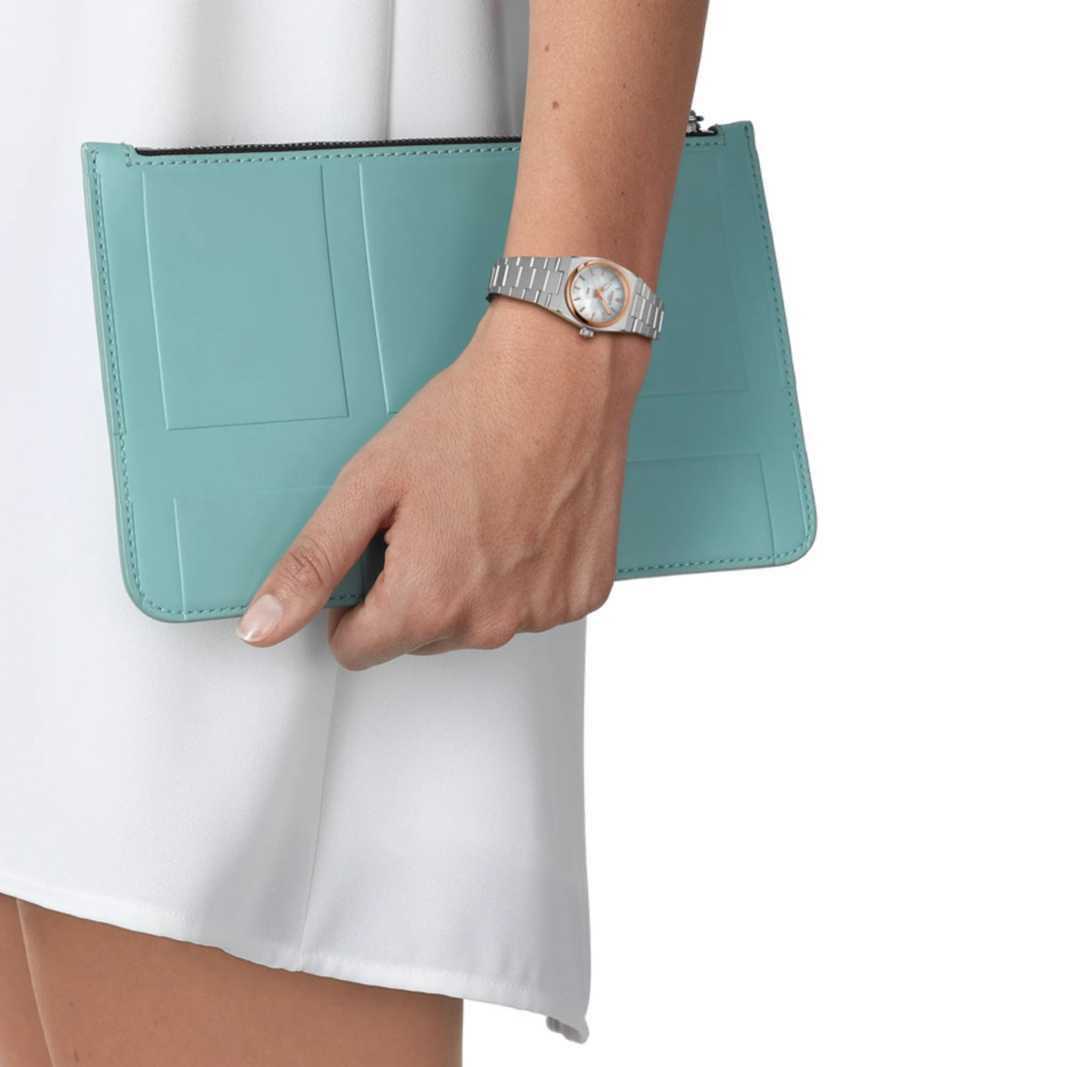 Hand holding a teal clutch with a white background