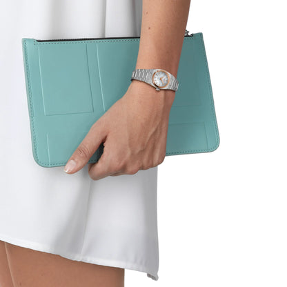 Hand holding a teal clutch with a white background