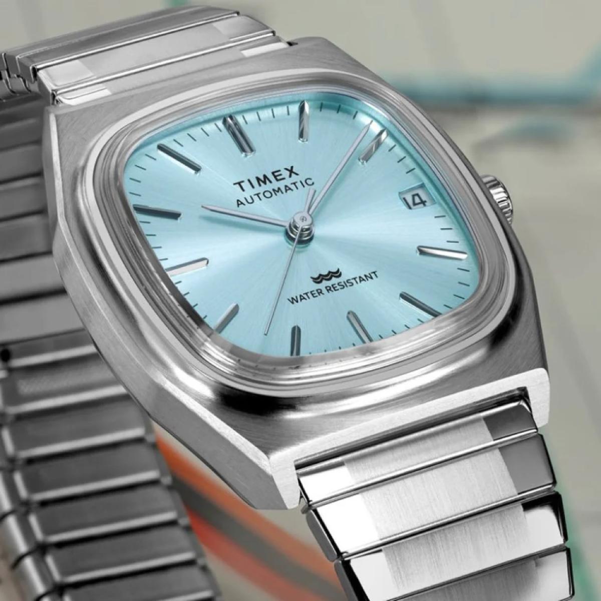 Timex watch with a light blue face and silver metal band on a blurred background
