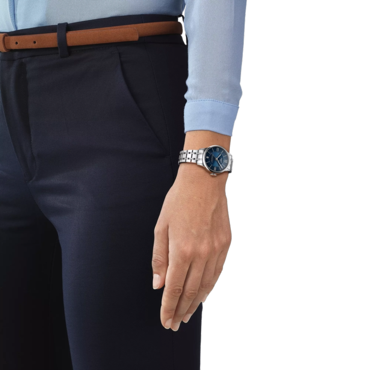 Hand wearing a watch with navy pants and light blue shirt on a white background