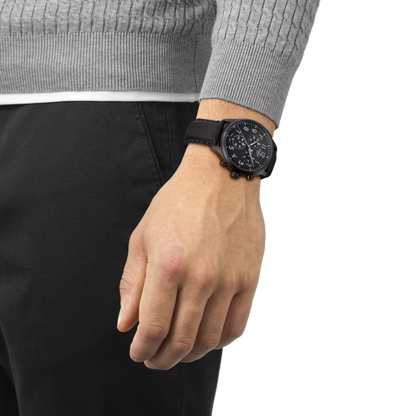 Person wearing a black wristwatch on a plain background